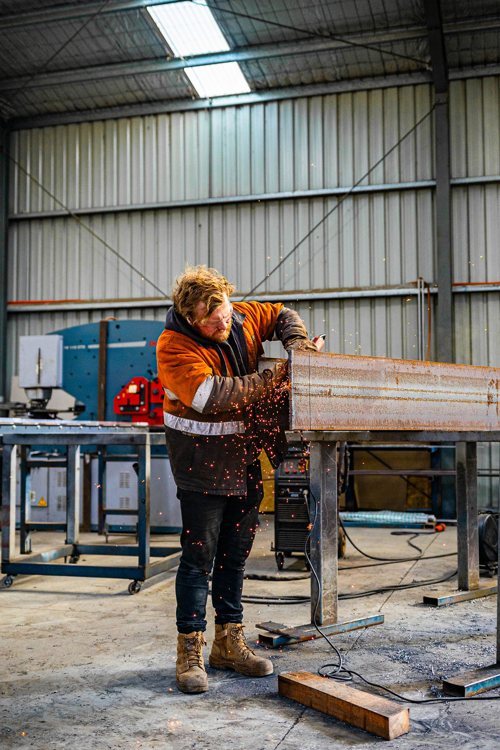 Fabricator grinding a steel beam in the workshop